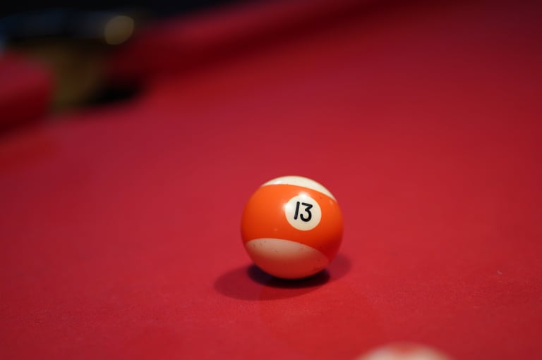 Orange number 13 billiard ball on red pool table felt with shallow depth of field