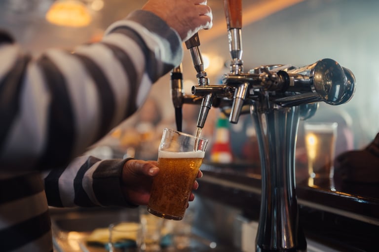 Bartender's hand pouring a fresh pint of golden craft beer