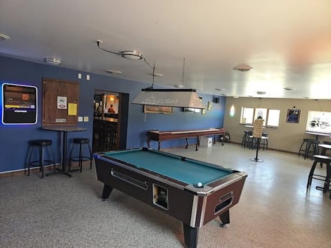 Recreation room with pool table, high-top seating area, and arcade game against blue walls
