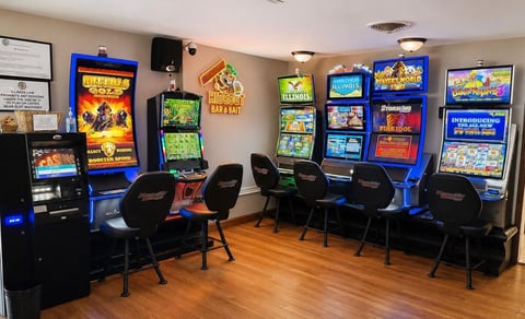 Retro arcade game room with vintage slot machines and gaming cabinets arranged around black gaming chairs on wooden flooring